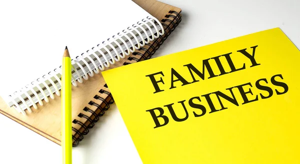 FAMILY BUSINESS text written on yellow paper with notebook