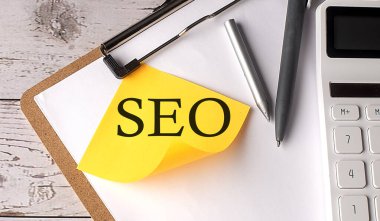 Hesap makinesi, kalem ve pano ile sarı yapışkan üzerinde SEO kelimesi