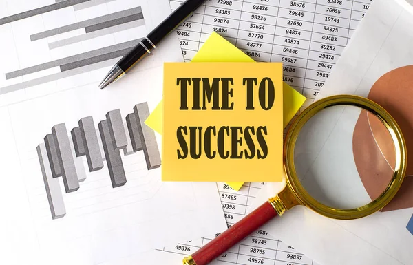 TIME TO SUCCESS text on sticky on the graph background with pen and magnifier