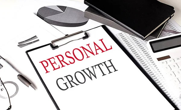 PERSONAL GROWTH text on paper clipboard with chart and notebook on a withe background