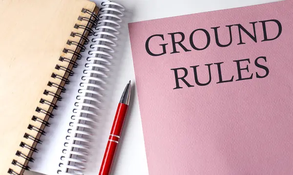 GROUND RULES word on pink paper with office tools on white background