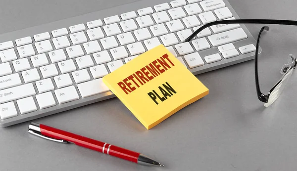 Retirement Plan Text Sticky Keyboard Pen Glasses Grey Background — Stock Photo, Image