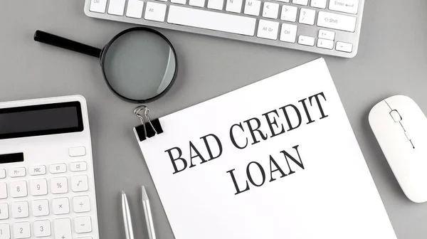 BAD CREDIT LOAN written on a paper with office tools and keyboard on the grey background
