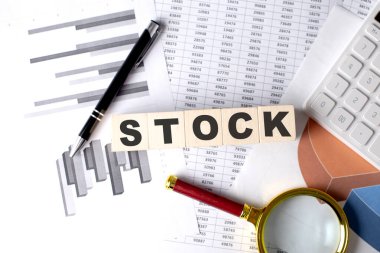 Grafik arkaplanındaki tahta blok üzerine kalem ve büyüteçle STOCK metni