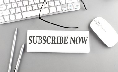 SUBSCRIBE Şimdi gri arkaplan üzerinde klavye ile bir kağıt üzerinde metin