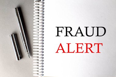 FRAUD ALERT text on notebook with pen on grey background clipart