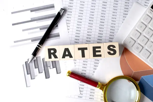 Grafik arkaplanındaki tahta blokta kalem ve büyüteçle RATES metni
