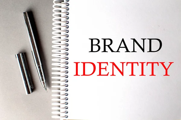 BRAND IDENTITY text on notebook with pen on grey background