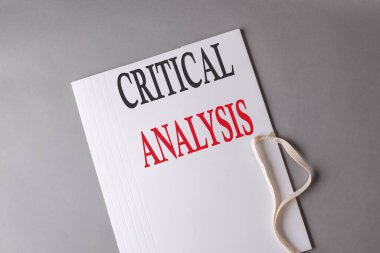 Gri arkaplanda beyaz bir klasör üzerindeki CRITICAL ANALYSIS metni