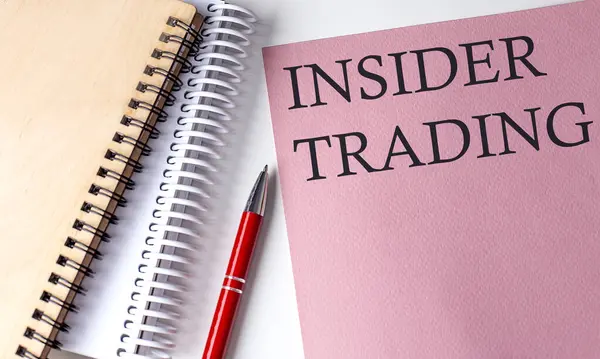 INSIDER TRADING word on pink paper with office tools on white background