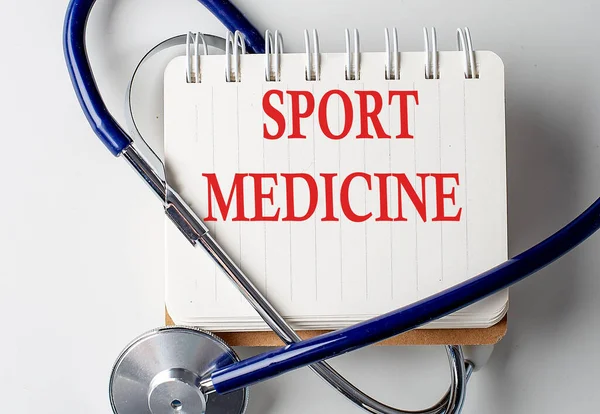 SPORT MEDICINE word on a notebook with medical equipment on background