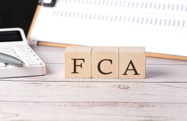 Tahta blokta pano ve hesap makinesiyle FCA sözcüğü