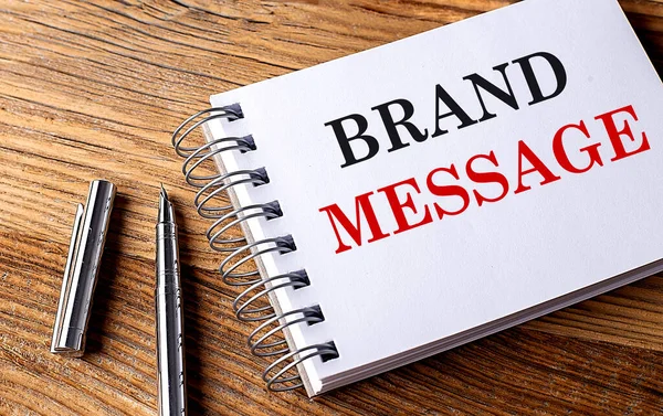 BRAND MESSAGE text on a notebook with pen on wooden background