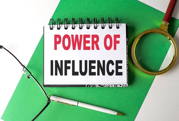 stock image POWER OF INFLUENCE text on a notebook on green paper