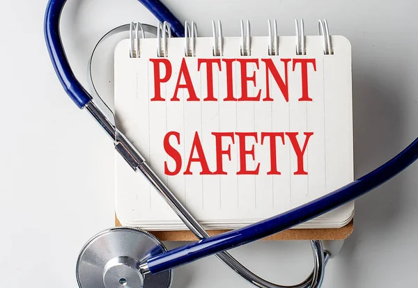 PATIENT SAFETY word on a notebook with medical equipment on background