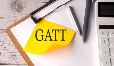 Hesap makinesi, kalem ve pano ile sarı yapışkan üzerine GATT kelime