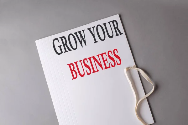 GROW YOUR BUSINESS text on a white folder on grey background