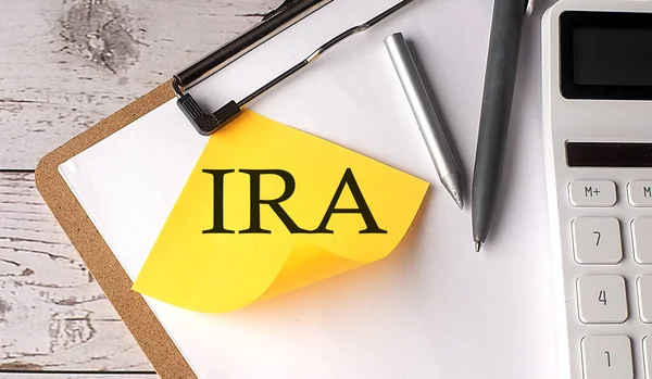 IRA word on yellow sticky with calculator, pen and clipboard