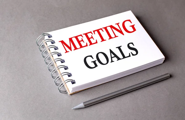 MEETING GOALS word on a notebook on grey background