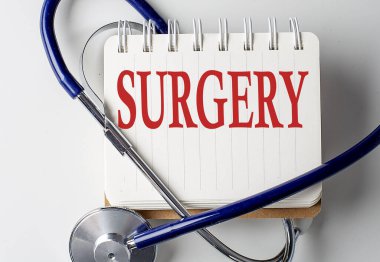 Arka planda tıbbi ekipman olan bir defterde SURGERY kelimesi