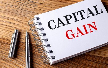 Ahşap zemin üzerinde kalem ile bir defter üzerinde CAPITAL GAIN metin