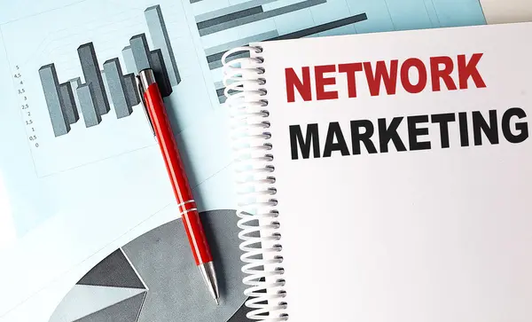 NETWORK MARKETING text on notebook with pen on a chart background