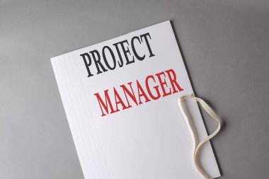 Gri arkaplanda beyaz bir dizin üzerinde PROJECT MANAGER metni