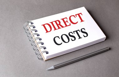 Gri arkaplandaki bir defterde DIRECT COSTS sözcüğü