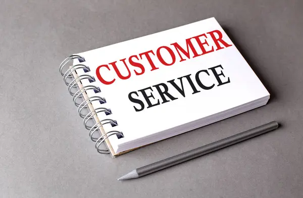 CUSTOMER SERVICE word on a notebook on grey background