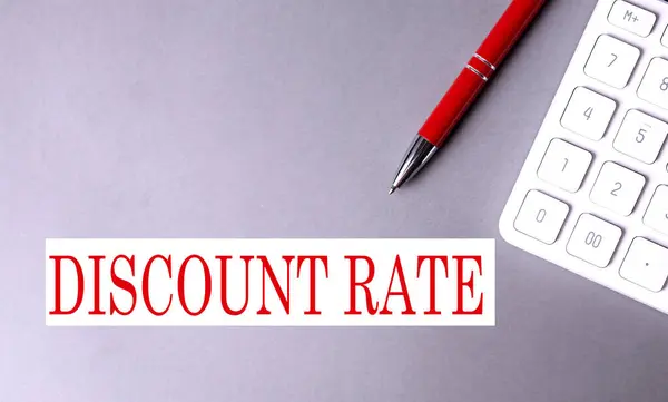 DISCOUNT RATE text written on gray background with pen and calculator