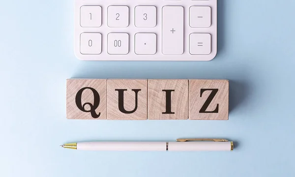 Kalem ve hesap makineli ahşap küplerde QUIZ, finansal konsept