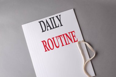 Gri arkaplanda beyaz klasör üzerindeki GÜNLÜK ROUTINE metni