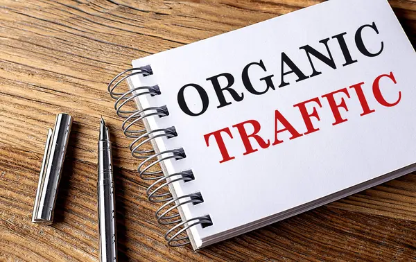 ORGANIC TRAFFIC text on a notebook with pen on wooden background