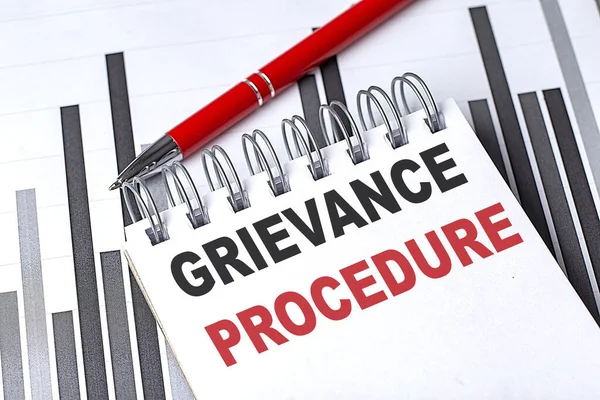 GRIEVANCE PROCEDURE çizelgesi üzerinde kalem olan bir deftere yazılmış metin