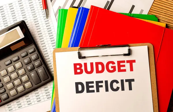 BUDGET DEFICIT text written on a paper clipboard with chart and calculator