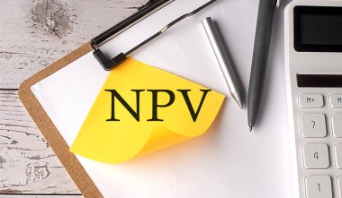 Hesap makinesi, kalem ve pano ile sarı yapışkan üzerine NPV kelimesi