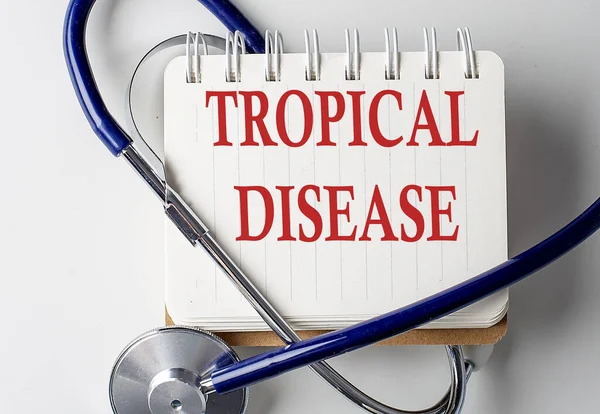 TROPICAL DISEASE word on notebook with medical equipment on a background