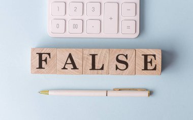 Kalem ve hesap makineli ahşap küplerin üzerinde FALSE, finansal konsept