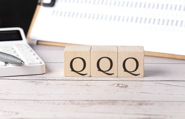 Tahta blokta pano ve hesap makinesiyle QQQ kelimesi