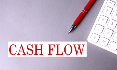 Gri arkaplanda kalem ve hesap makinesiyle yazılmış CASHFLOW metni