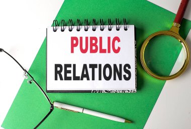 Yeşil kağıt üzerinde bir defter üzerinde POBLIC İlişkiler metni