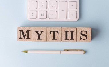 Kalem ve hesap makineli tahta küplerde MYTHS, finansal konsept