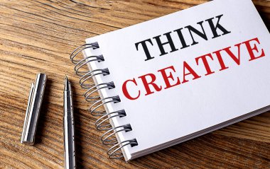 Tahta zemin üzerinde kalem olan bir defter üzerinde yaratıcı bir metin düşünün