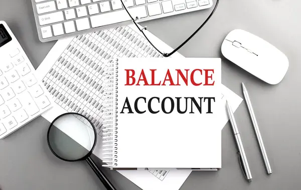 BALANCE ACCOUNT text on a notebook with keyboard and calculator on a chart background