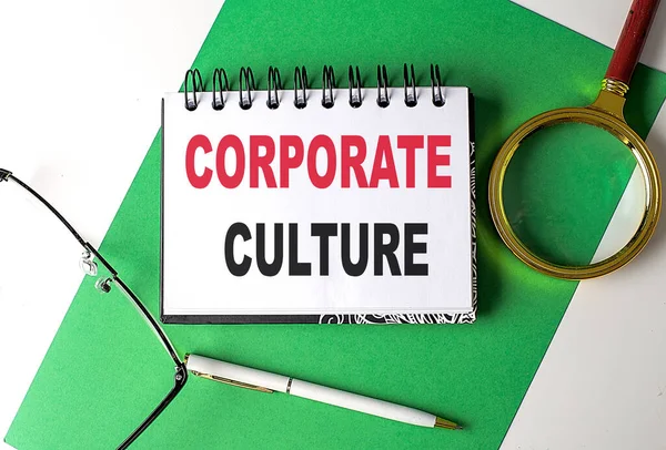 CORPORATE CULTURE text on a notebook on green paper