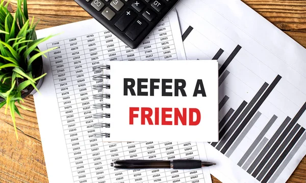 REFER A FRIEND text on notebook with chart and calculator