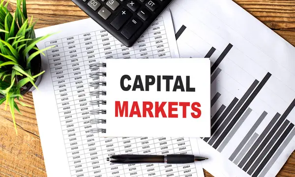 CAPITAL MARKETS text on notebook with chart and calculator