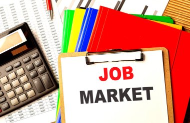 Dosya ve hesap makinesiyle kağıt panoya yazılmış JoB MARKET metni