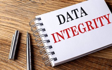 Tahta zemin üzerinde kalem bulunan bir not defterindeki DATA INTEGRITY metni