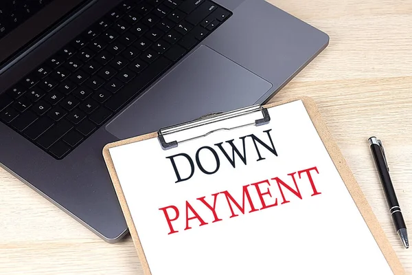 DOWN PAYMENT text written on paper clipboard on laptop
